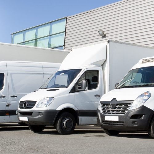 delivery white vans in service van trucks and cars in front of the entrance of a warehouse distribution logistic society